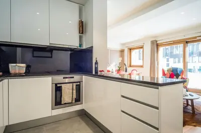 a kitchen with white cabinets and a black counter top at Grand Paradis in Chamonix-Mont-Blanc