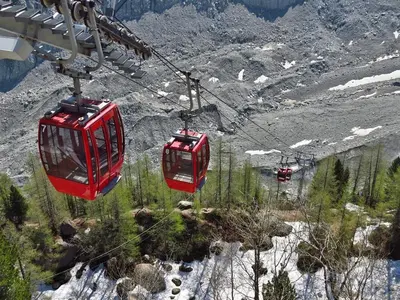 two red cable cars flying over a mountain at Apartment Triolet Jardin - Garden with Mont Blanc Views in Chamonix-Mont-Blanc