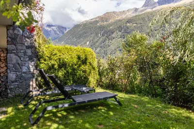 two chairs and a table in front of a mountain at Auberge du Bois Prin in Chamonix-Mont-Blanc