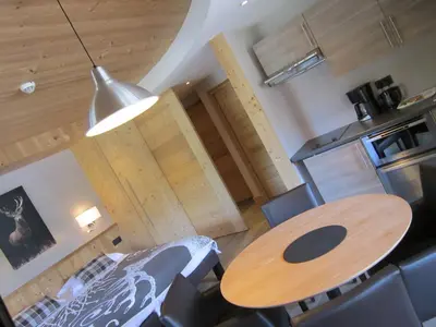 a room with a table and chairs and a kitchen at Logis Hotel Gai Soleil in Samoëns