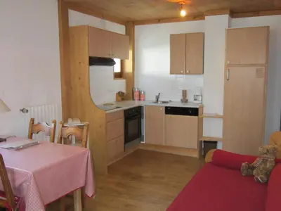 a small kitchen with a table and a dining room at Logis Hotel Gai Soleil in Samoëns
