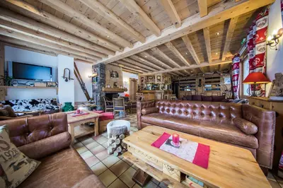 a living room with leather couches and a table at Logis Hotel Gai Soleil in Samoëns