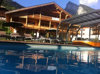 a hotel with a swimming pool in front of a building at Logis Hotel Gai Soleil in Samoëns