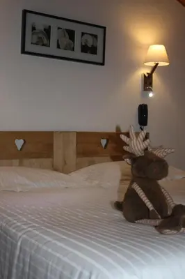 a stuffed teddy bear sitting on a bed at Logis Hotel Gai Soleil in Samoëns