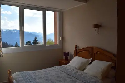 a bedroom with a bed and a window with mountains at Résidence Le Fontenay in Plateau dʼAssy