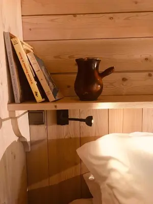 a shelf with books and a vase on it next to a bed at Le Cerf Amoureux Chalet Privé & Spa in Sallanches