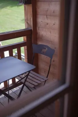 a table and a chair on the porch of a cabin at Le Cerf Amoureux Chalet Privé & Spa in Sallanches