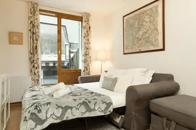 a bedroom with a bed and a chair and a window at Apartment Balme 2 - Central Chamonix Haven and Mont Blanc View in Chamonix-Mont-Blanc