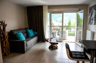 a living room with a couch and a large window at Appartement au pied du Mont-Blanc ! in Sallanches