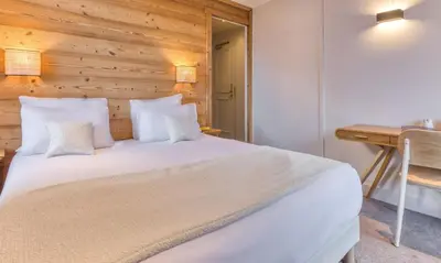 a bedroom with a white bed with a wooden wall at Hôtel Lyret in Chamonix-Mont-Blanc