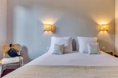 a bedroom with a white bed with two lights at Hôtel Lyret in Chamonix-Mont-Blanc