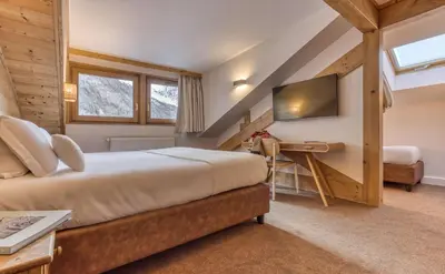 a bedroom with a bed and a desk and a television at Hôtel Lyret in Chamonix-Mont-Blanc