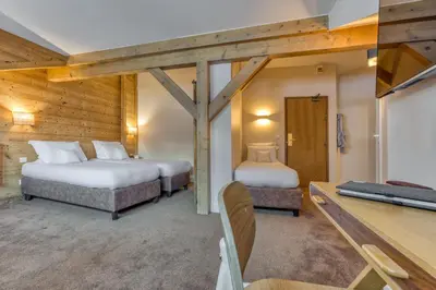 two beds in a room with a tv and a room with at Hôtel Lyret in Chamonix-Mont-Blanc