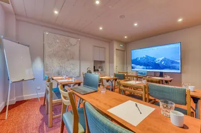 a classroom with tables and chairs and a large screen at Hôtel Lyret in Chamonix-Mont-Blanc
