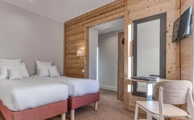a bedroom with a bed and a desk and a television at Hôtel Lyret in Chamonix-Mont-Blanc