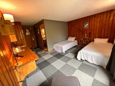 a hotel room with two beds and a checkered floor at Fontaine du Mont Blanc Hotel & Spa in Les Houches
