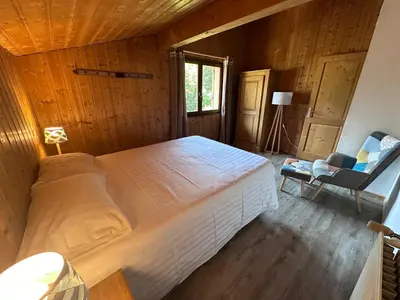 a bedroom with a large bed and a chair at Fontaine du Mont Blanc Hotel & Spa in Les Houches