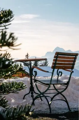 a bench and a table with a view of the mountains at La Ferme du Golf in Megève