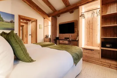 a bedroom with two beds and a flat screen tv at La Ferme du Golf in Megève