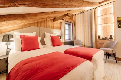 a hotel room with two beds and a television at La Ferme du Golf in Megève