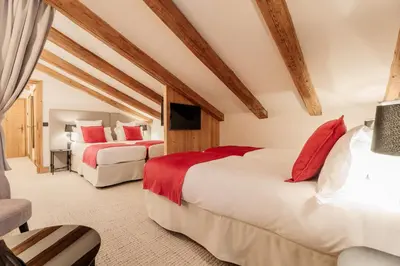 two beds with red pillows in a room at La Ferme du Golf in Megève
