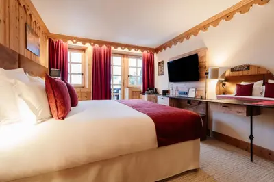 a bedroom with a white bed and a tv at La Ferme du Golf in Megève