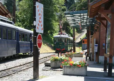 a train pulling into a train station with a stop sign at Les Jardins Alpins - Apartment in Saint-Gervais-les-Bains