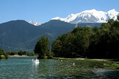 a boat on a lake with mountains in the background at Les Jardins Alpins - Apartment in Saint-Gervais-les-Bains