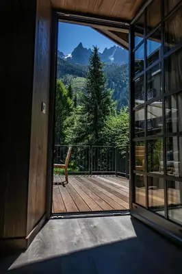 an open door to a balcony with a view of the mountains at Le Hameau Albert 1er - Relais & Châteaux in Chamonix-Mont-Blanc