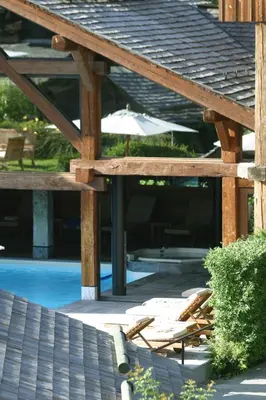 a patio with chairs and an umbrella next to a pool at Le Hameau Albert 1er - Relais & Châteaux in Chamonix-Mont-Blanc