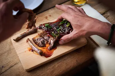 a person holding a piece of meat on a cutting board at Vert Lodge Chamonix in Chamonix-Mont-Blanc