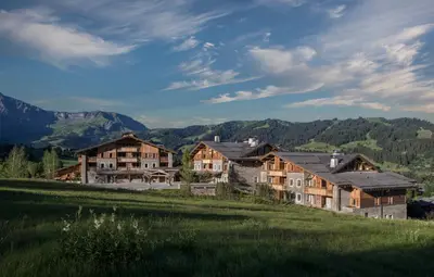 a group of houses in a field with mountains in the background at Four Seasons Resort Megève in Megève