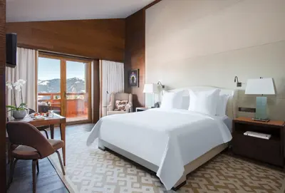 a hotel room with a large white bed and a desk at Four Seasons Resort Megève in Megève