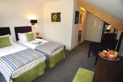 a hotel room with two beds and a table with a plate of fruit at Hotel Les Lanchers in Chamonix-Mont-Blanc