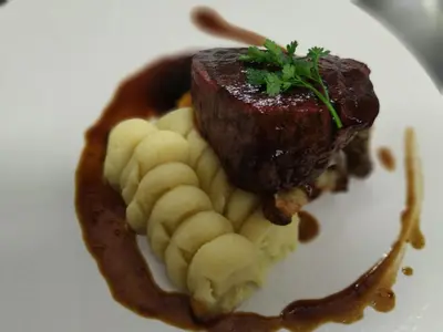 a plate of food with a piece of meat and bananas at Hotel Les Lanchers in Chamonix-Mont-Blanc