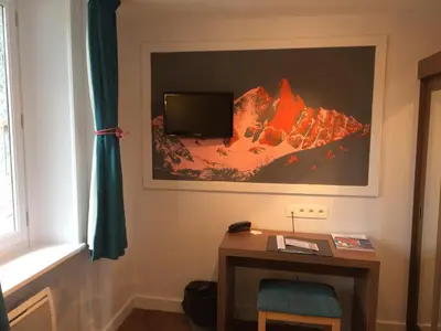 a room with a desk and a tv on the wall at Hotel Les Lanchers in Chamonix-Mont-Blanc