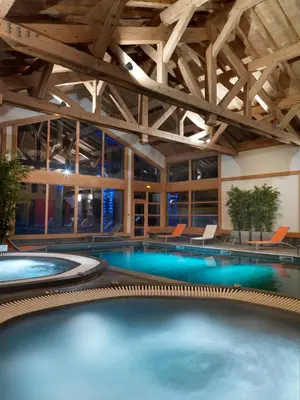 a large swimming pool in a building with wooden ceilings at CGH Résidences & Spas La Reine des Prés in Samoëns