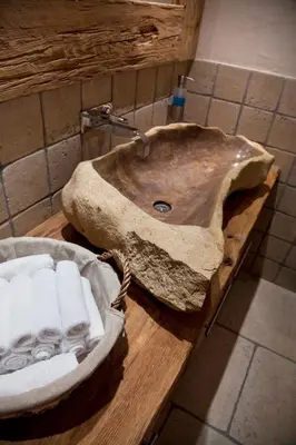a stone sink on a wooden counter in a bathroom at CGH Résidences & Spas La Reine des Prés in Samoëns