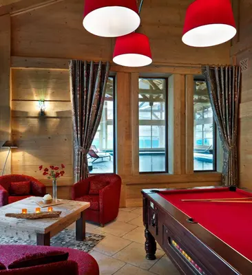 a billiard room with a pool table and red chairs at CGH Résidences & Spas La Reine des Prés in Samoëns
