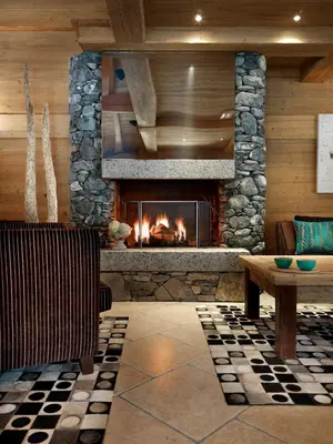 a fireplace in a room with a bench and a table at CGH Résidences & Spas La Reine des Prés in Samoëns
