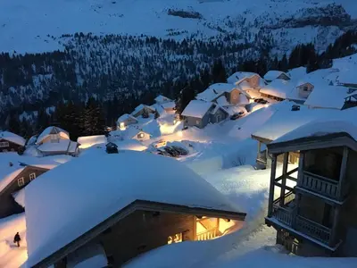 a balcony with a table and a view of snow covered mountains at Dormio Resort Les Portes du Grand Massif in Flaine