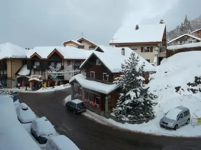a snow covered building with cars parked in front of it at résidence Le Platé in Les Carroz d'Araches