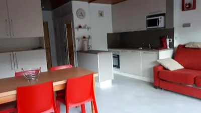 a kitchen with a wooden table and red chairs at résidence Le Platé in Les Carroz d'Araches