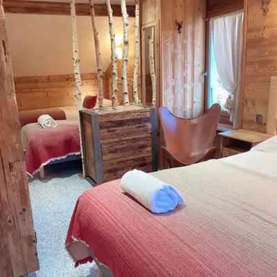a bedroom with two beds and a desk and a chair at Hôtel Les Cimes in Megève