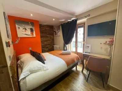 a bedroom with an orange wall and a bed and a desk at Hôtel Les Cimes in Megève
