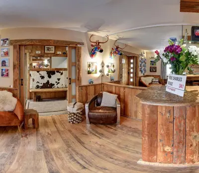 a living room with wood floors and a room with a table at Hôtel Les Cimes in Megève