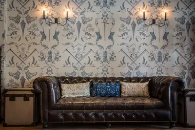 a brown leather couch in a room with wallpaper at Pointe Isabelle in Chamonix-Mont-Blanc