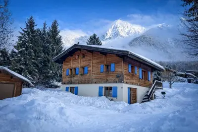 a log cabin in the snow with a mountain in the background at Chalet Les Frenes in Chamonix-Mont-Blanc