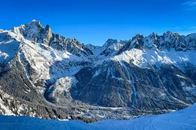 a snow covered mountain range with a lake in the foreground at Chalet Les Frenes in Chamonix-Mont-Blanc