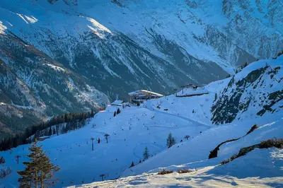 a snow covered mountain with a house on a hill at Chalet Les Frenes in Chamonix-Mont-Blanc